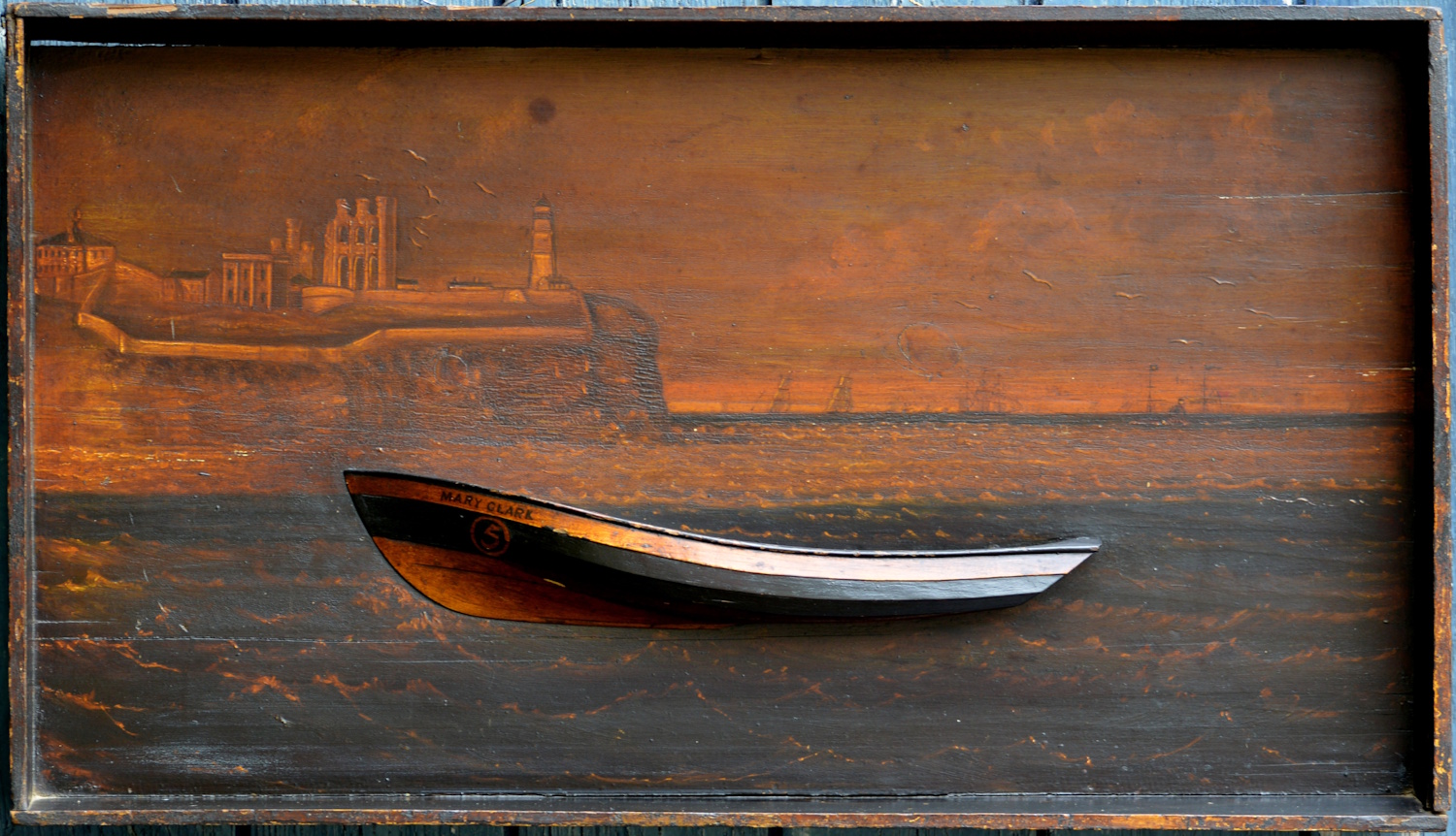 A 19th century Folk Art carved and painted half model Hull of a Coble with Tynemouth Castle and Priory in the Background